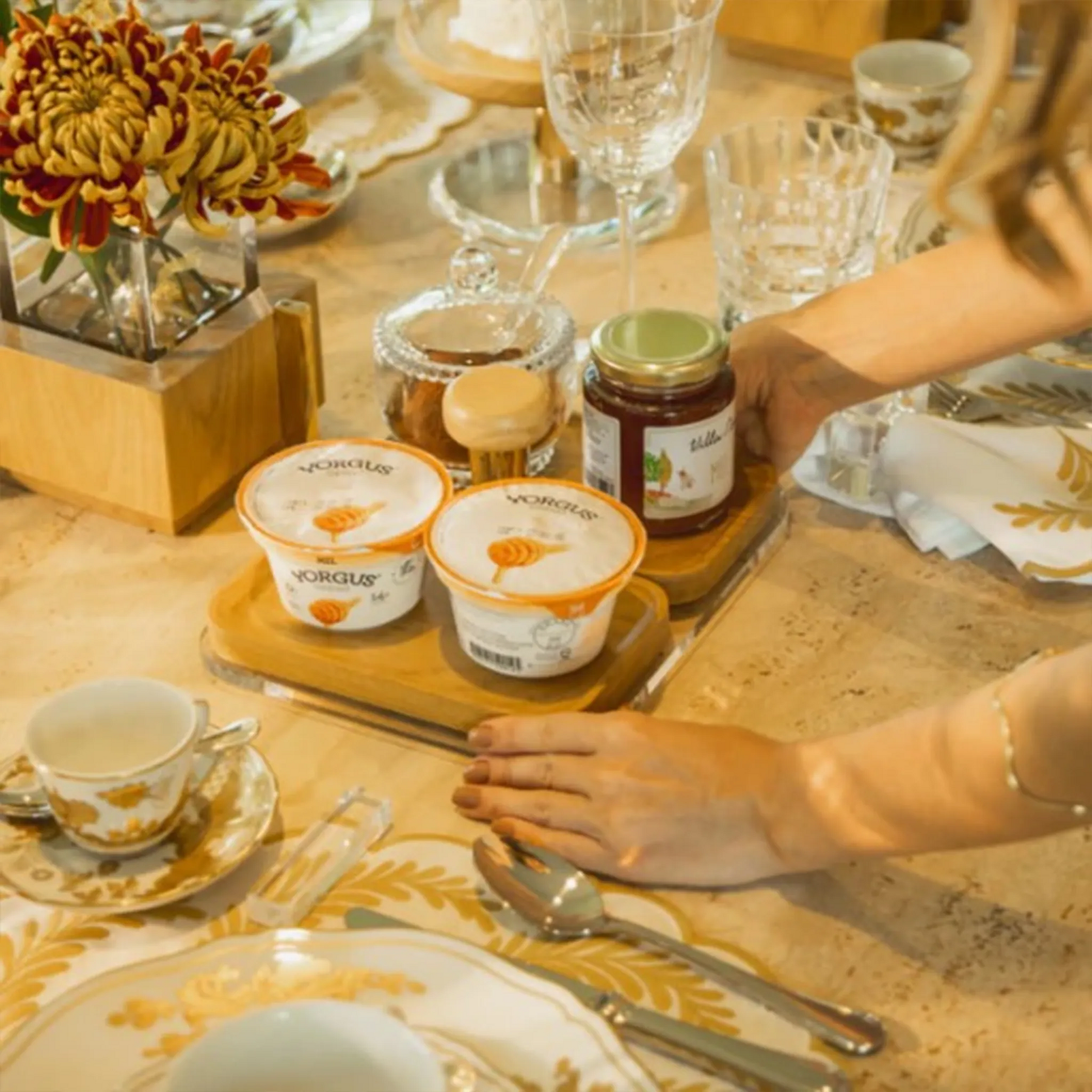 Base de Apoio Tauari Alenya ambientada em cima de mesa de madeira, carregada por uma mulher.