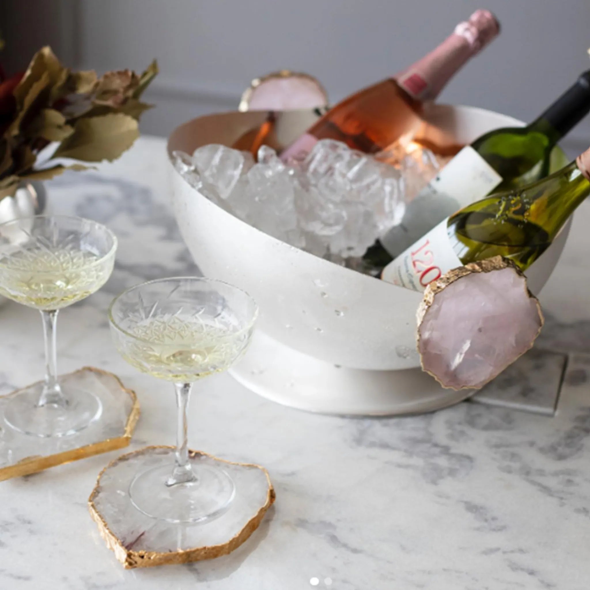 Mesa de pedra com taças de cristal e  Champanheira com Pedra, ao lado de um arranjo de flores.