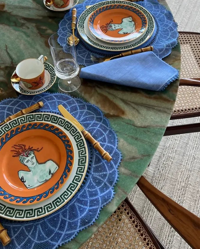 Acessórios da marca Casa DV sobre mesa de pedra e composição de pratos.