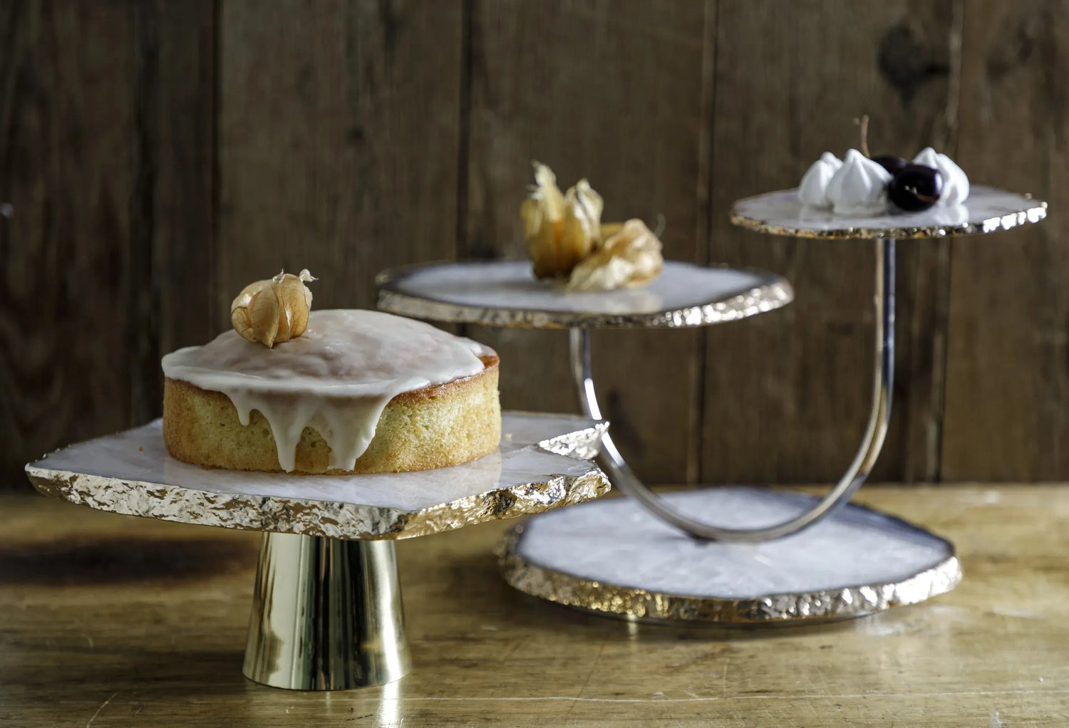 Boleiras da marca Home Wish com bolos em cima sobre mesa de madeira.