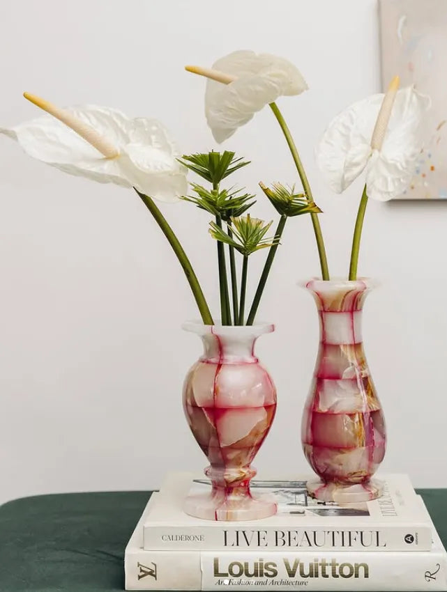 Vasos da marca Home Wish sobre livros e com flores dentro.