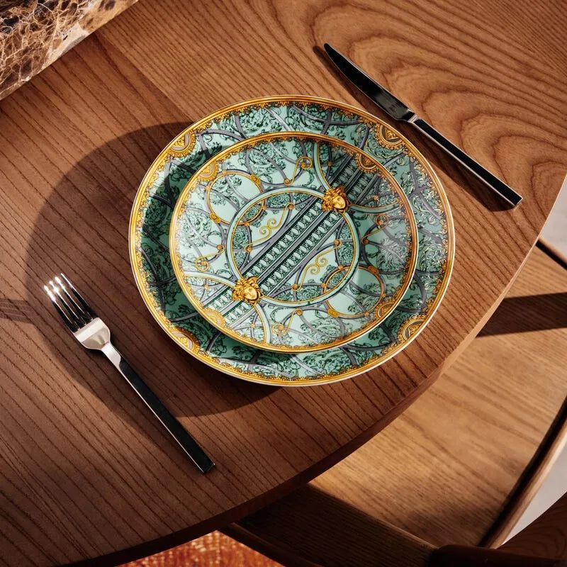 Mesa de madeira com pratos da marca Versace Home e talheres.
