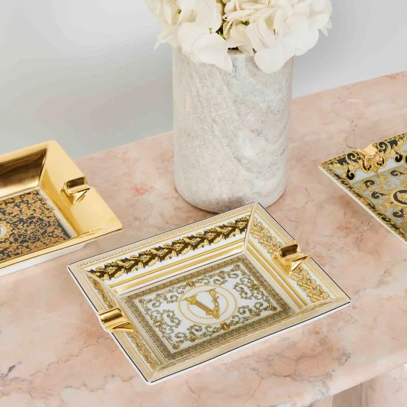 Mesa de pedra ambientada com produtos de decoração da marca Versace Home.