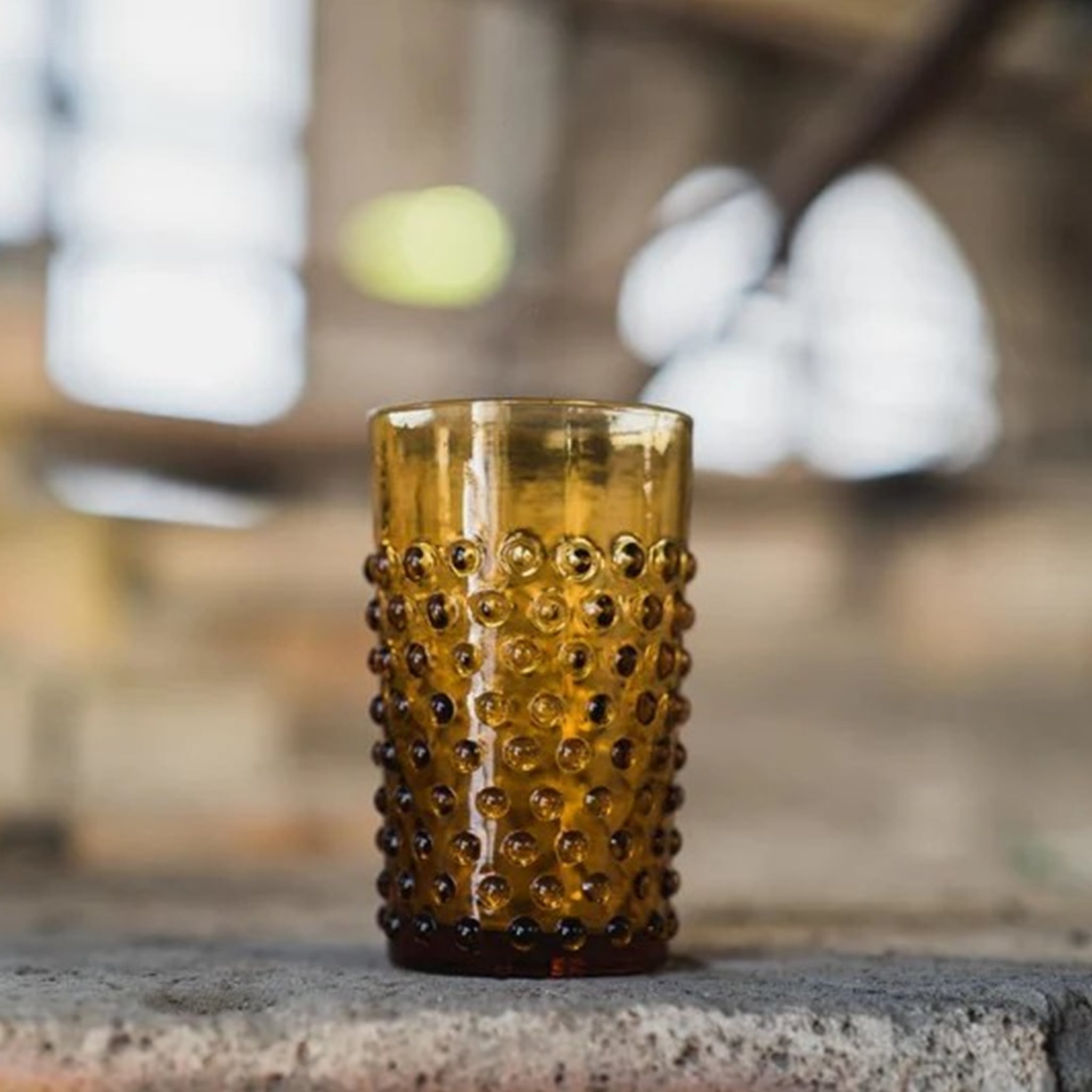 Copo Curto Hobnail Âmbar em cima de uma pedra.