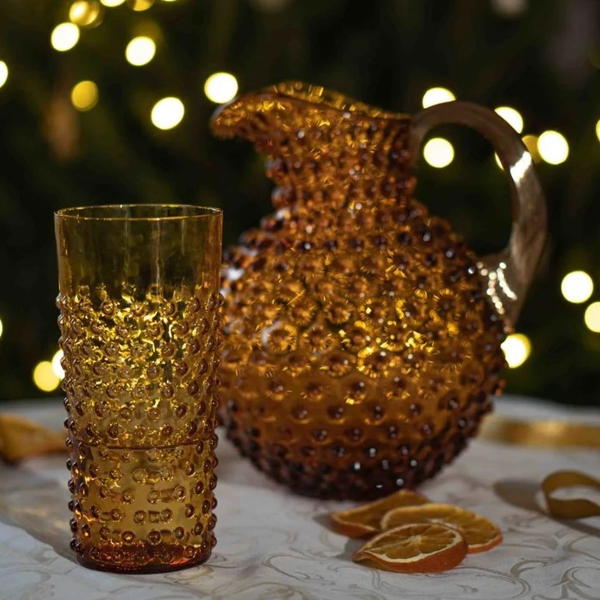 Copo Longo Hobnail Âmbar com a jarra da mesma coleção em ambiente noturno.