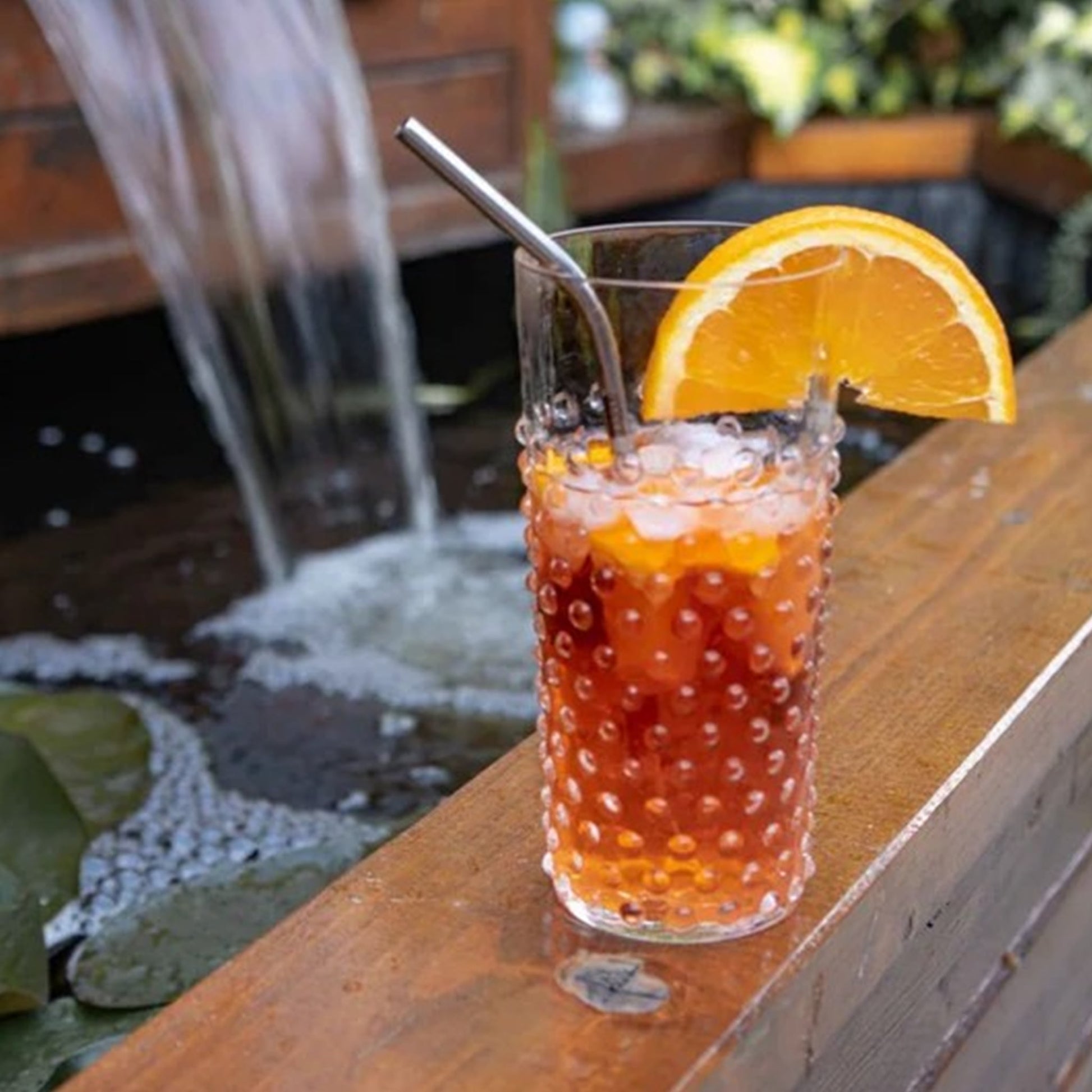 Copo Longo Hobnail Cristal em ambiente aberto com uma bebida refrescante dentro.