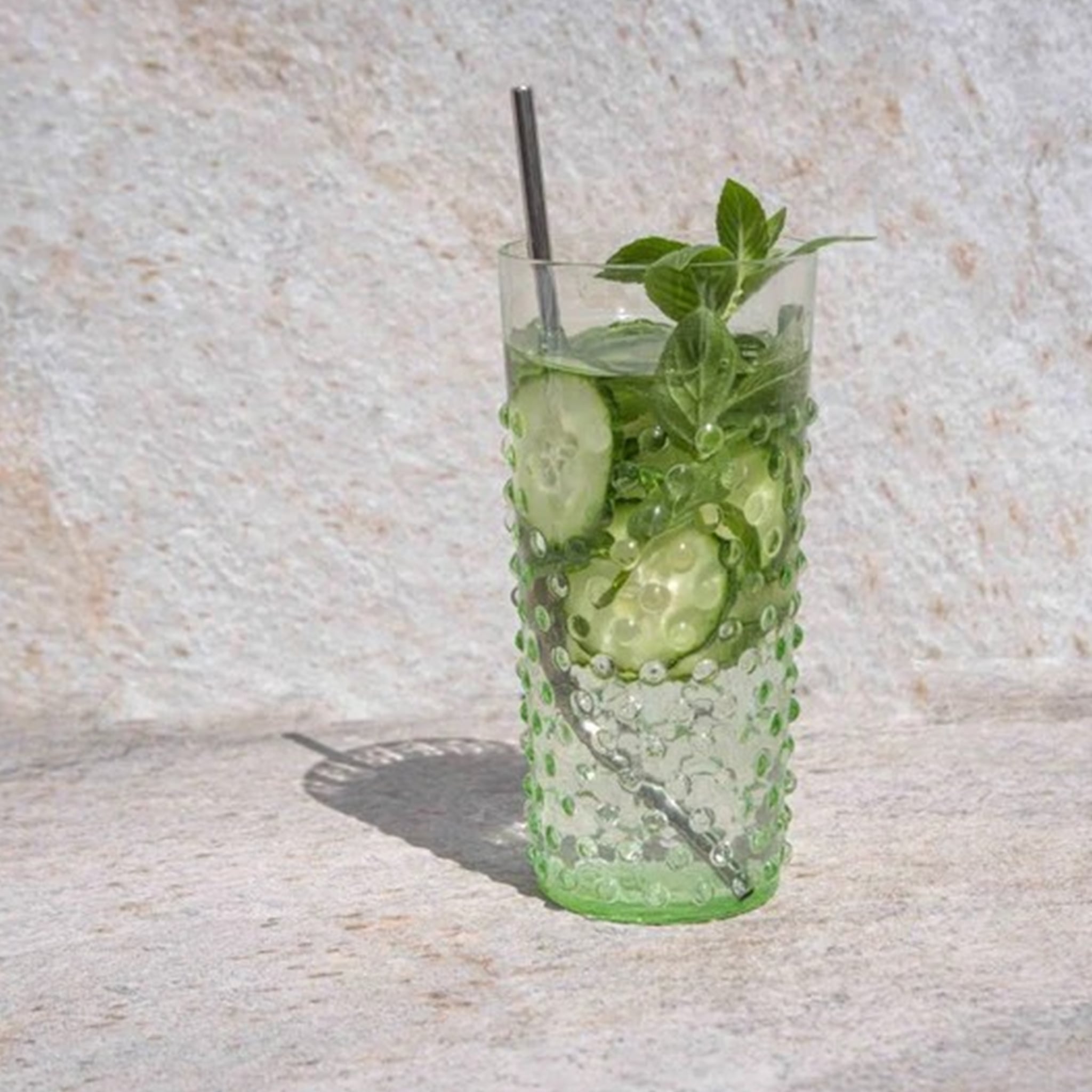 Copo Longo Hobnail Verde Claro com bebida refrescante dentro e pepinos.