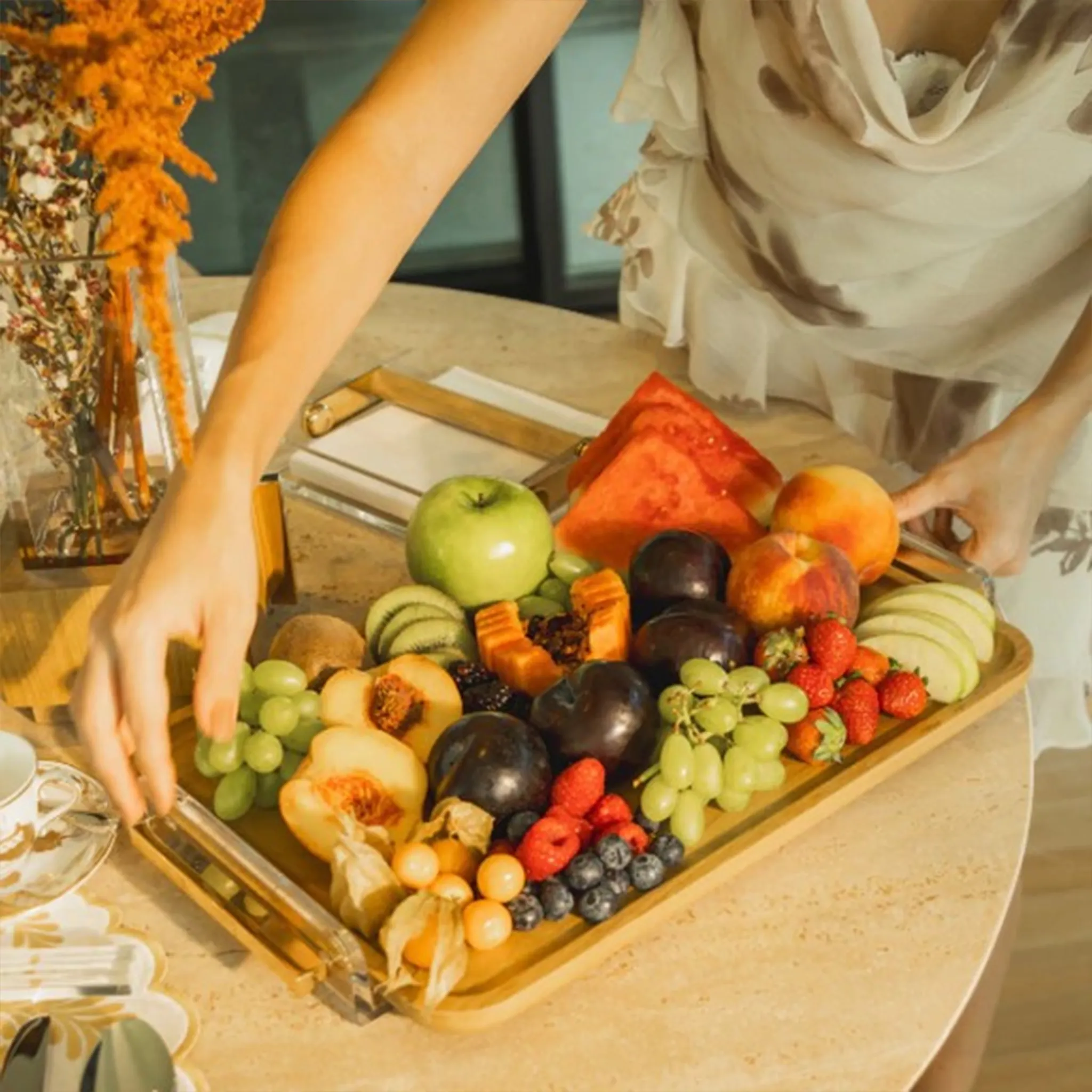 Bandeja Tauari Alenya ambientada com frutas e carregada por uma mulher.
