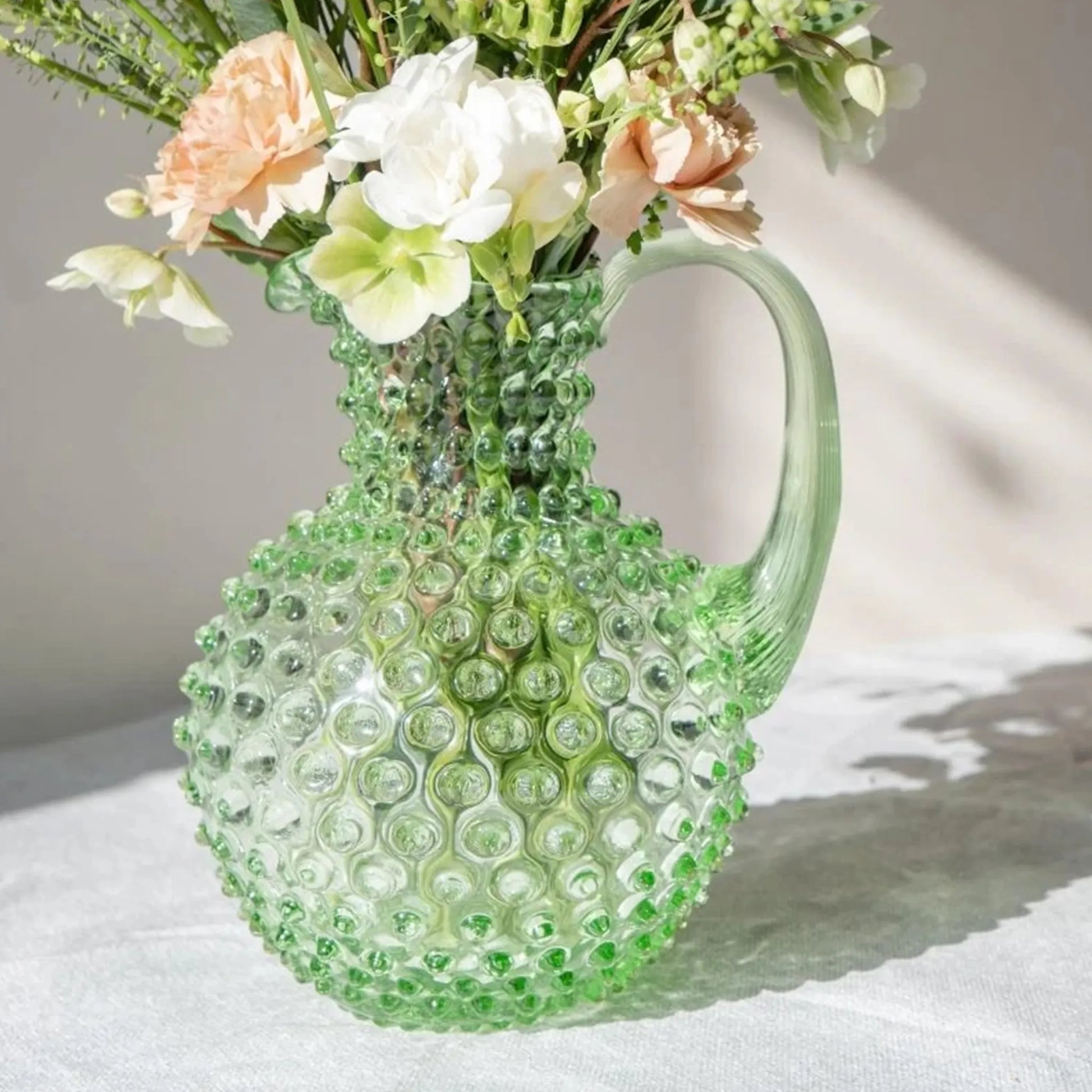 Jarra Hobnail Verde Claro 2L ambientada com flores dentro.