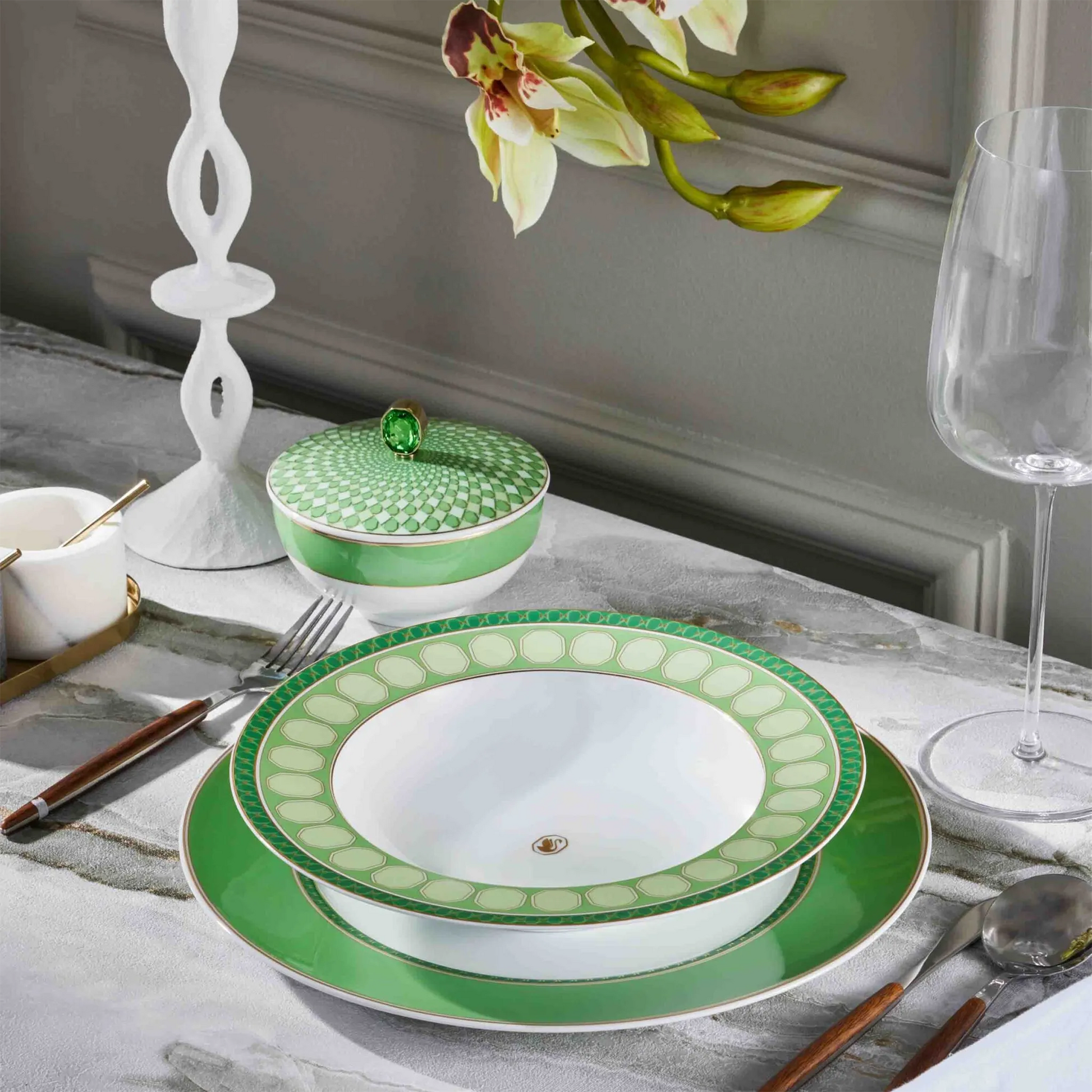 Conjunto de aparelhos de jantar Swarovski Verde em cima de mesa de pedra, com taças de cristal.