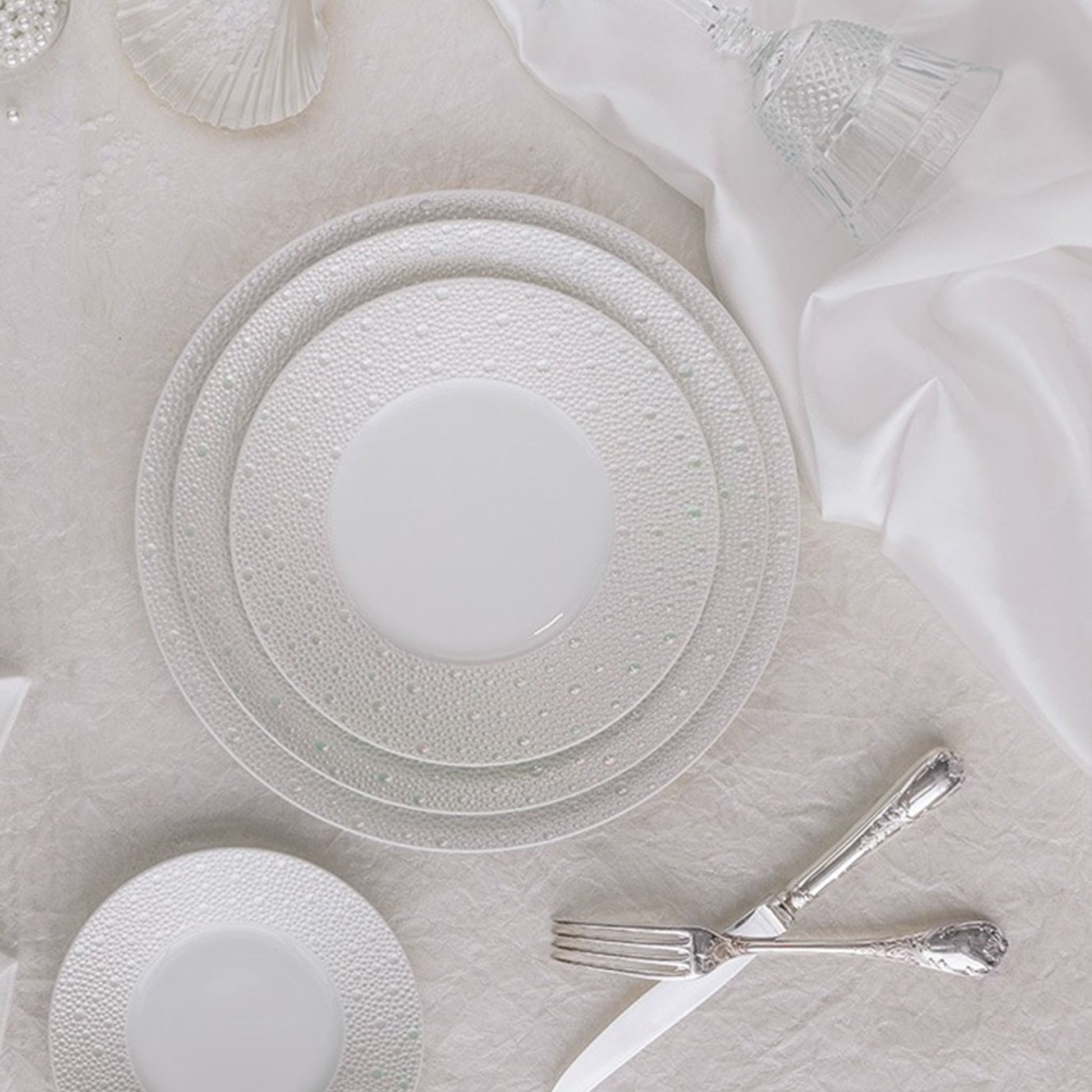 Cena ambientada de pratos da coleção Ecume Pérola sobre uma mesa.