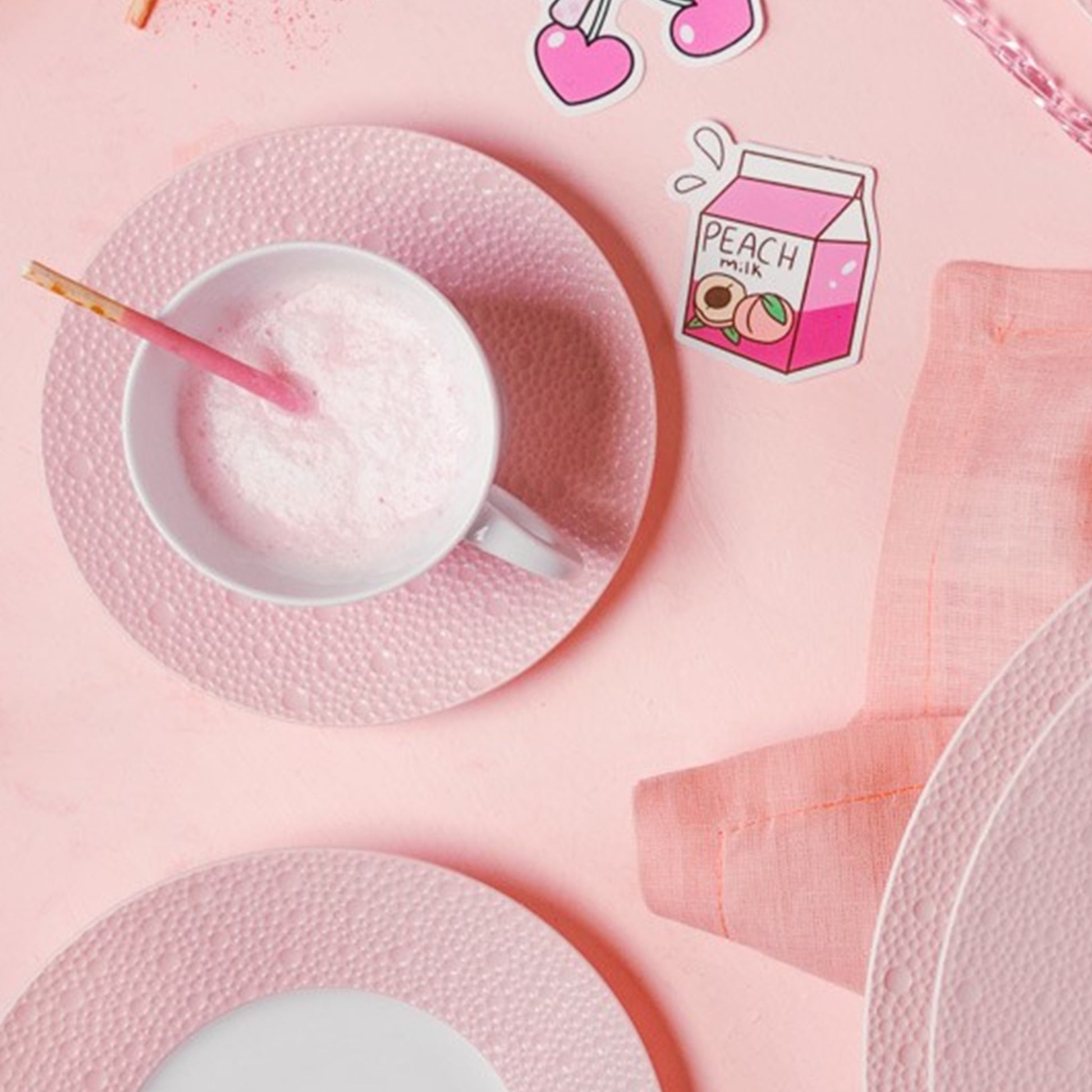 Xícara e pratos da coleção Ecume Rosa, ambientado em mesa com adereços do mesmo tom.