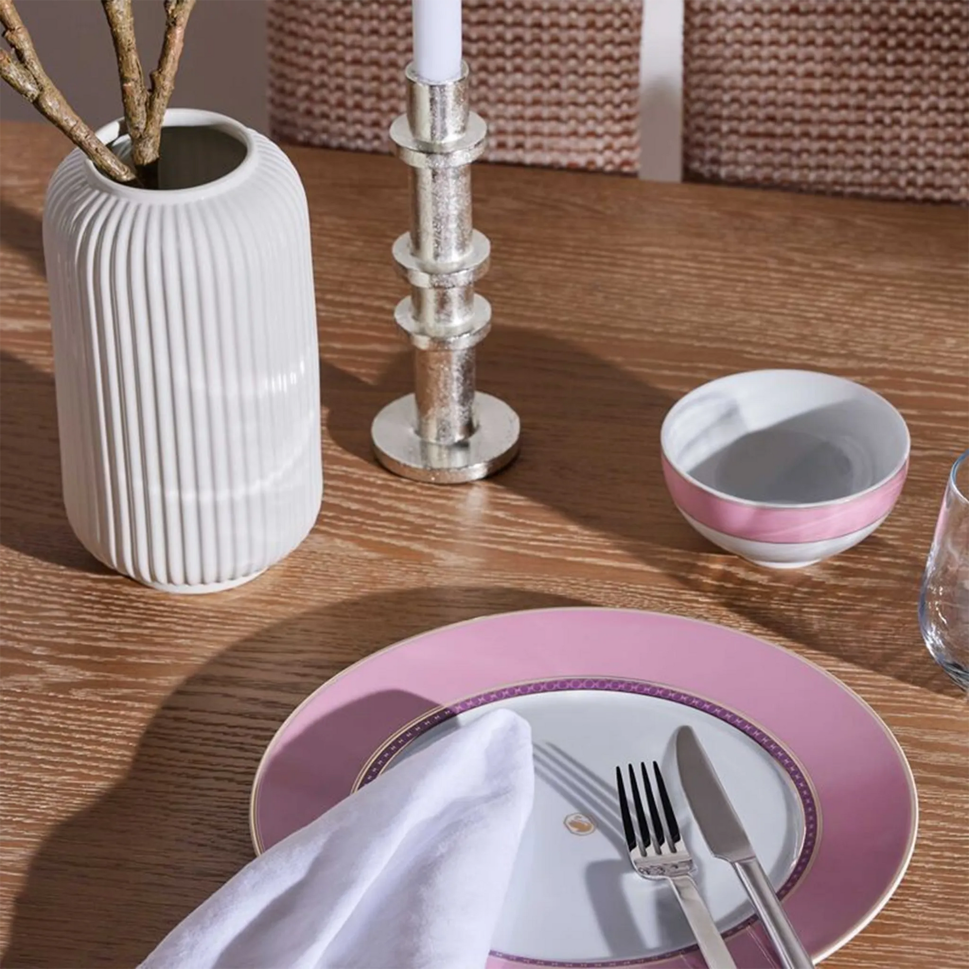 Prato Raso Swarovski Rosa ambientado em mesa de madeira, com utensílios de jantar.