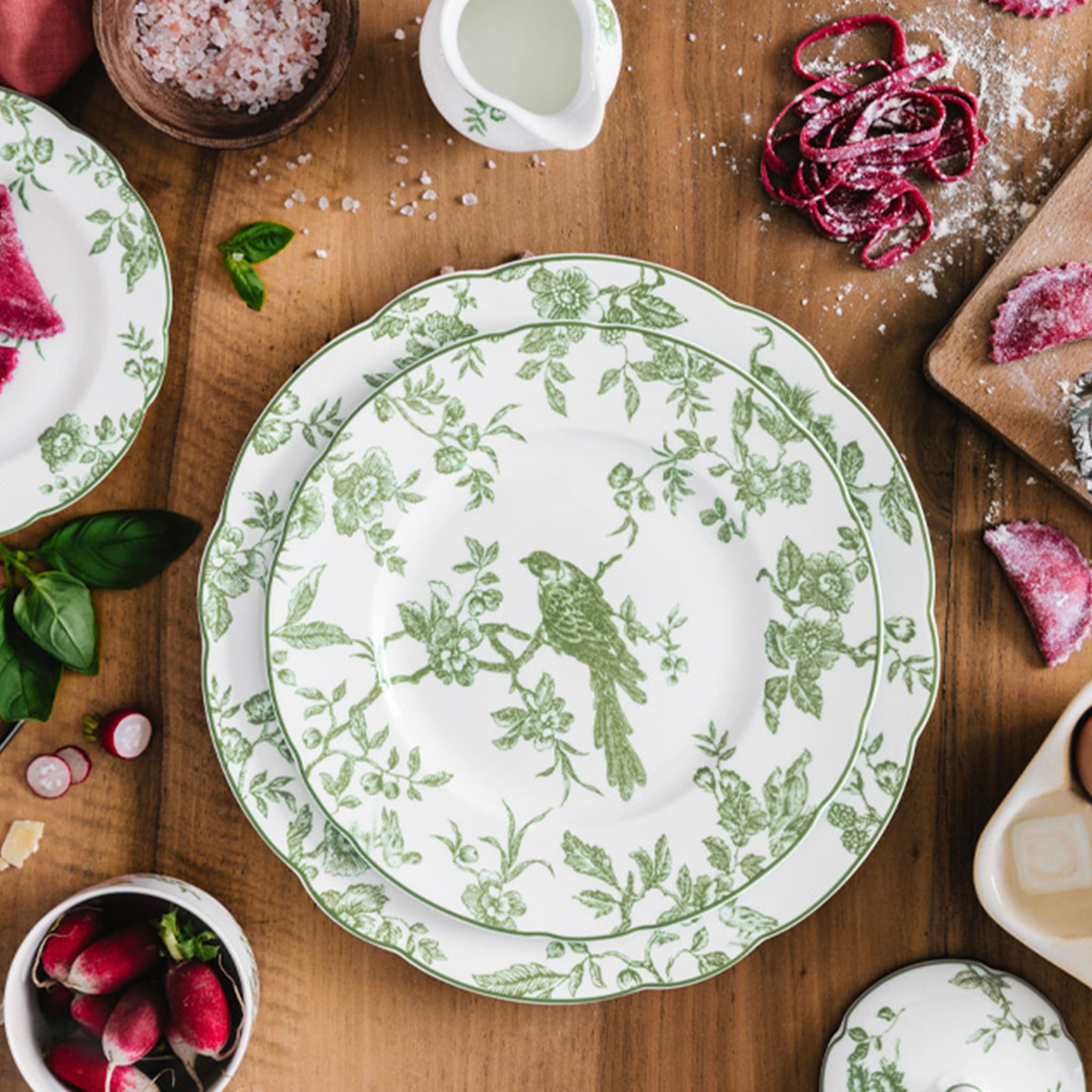 Pratos da coleção Albertine em cima de uma mesa de madeira com adornos rústicos ao redor.
