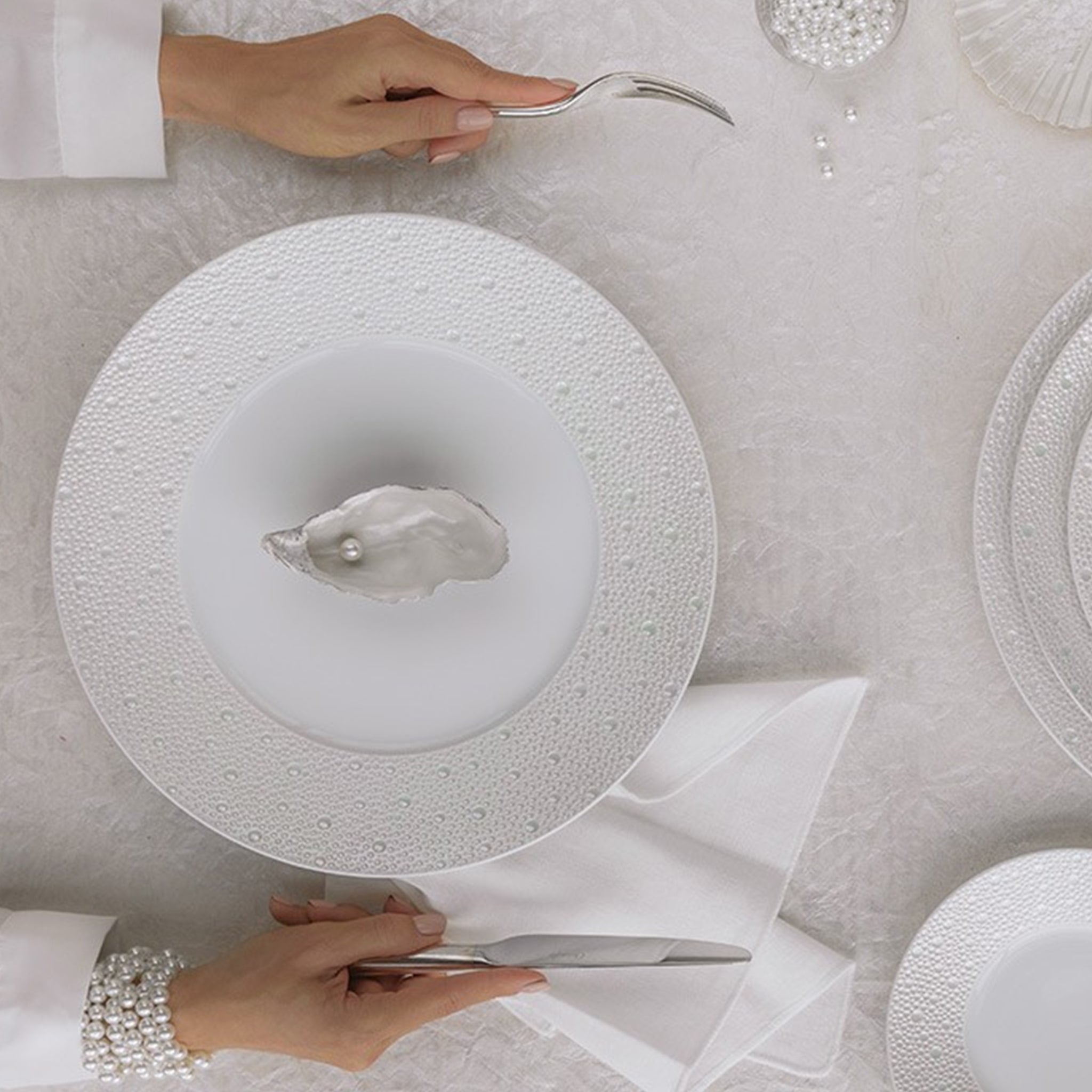 Prato Sobremesa Ecume Pérola ambientado em mesa com talhes e pérolas.