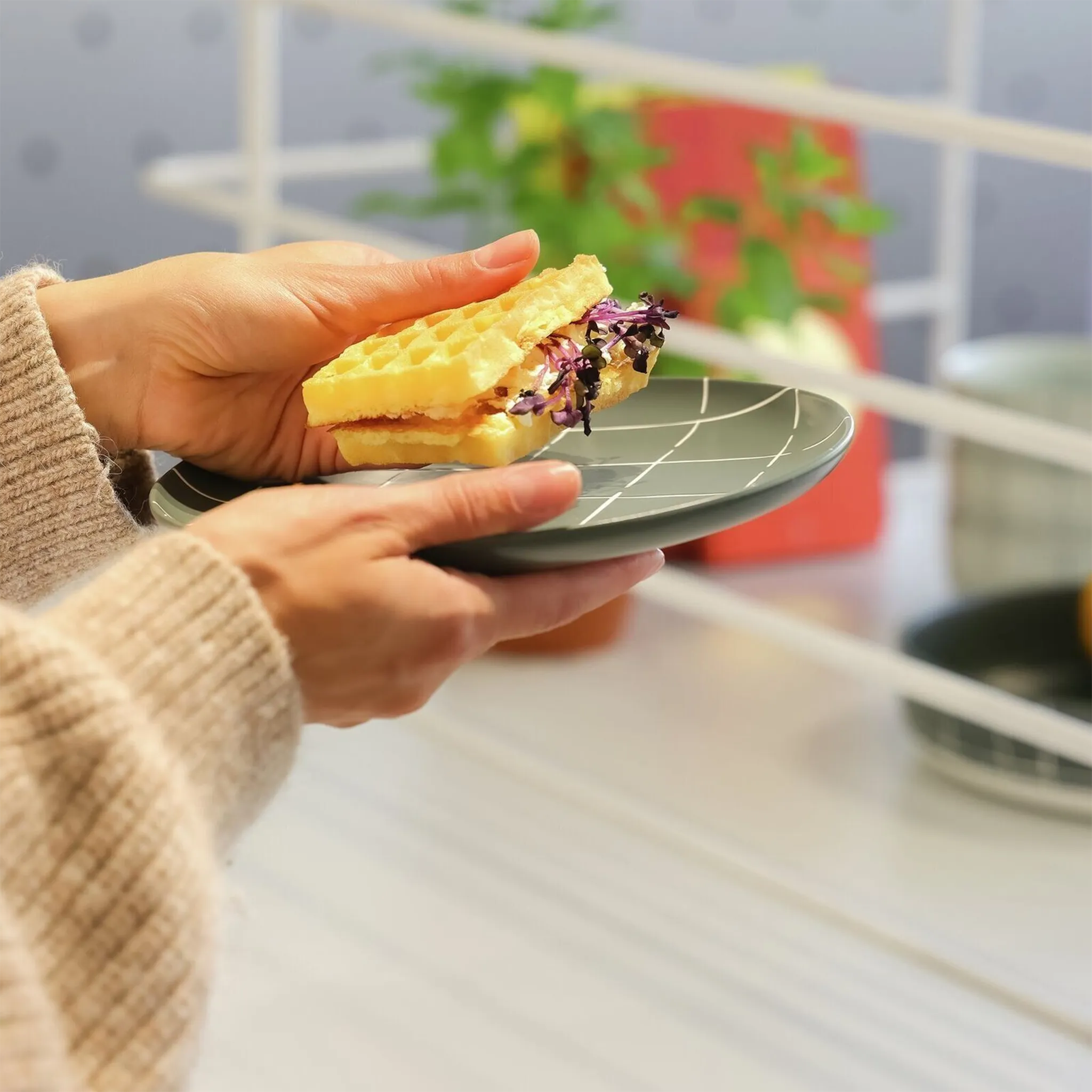 Mulher segurando o Prato Sobremesa Karo Verde Escuro com um sanduíche.