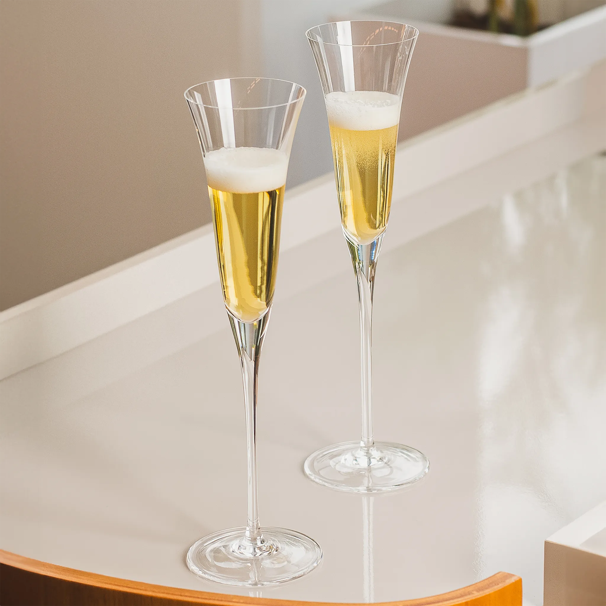 Taças Champanhe Liso em cima de uma mesa de vidro.