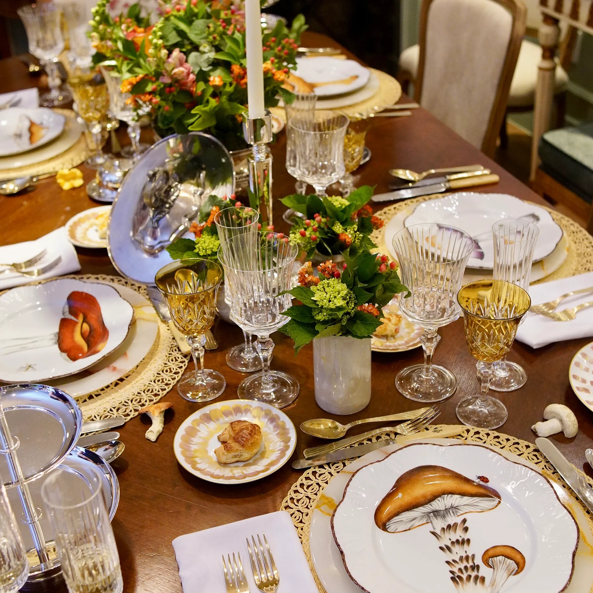 Mesa posta com pratos, taças de cristal, flores, velas, talheres e Set Descanso de Talher Cogumelo Colorido.