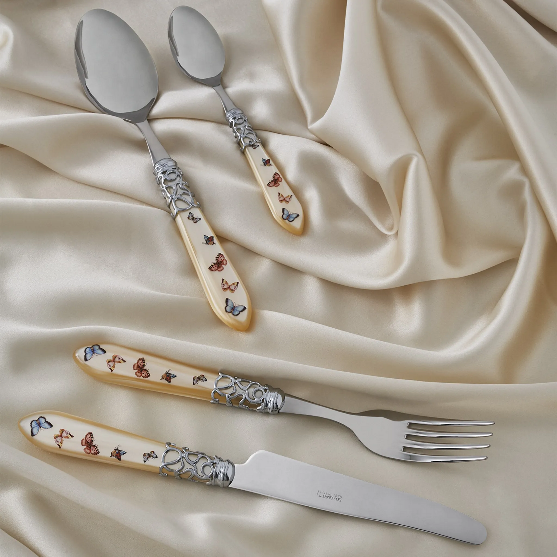 Set Faqueiro Melodia Borboleta Bugatti Ivory em cima de tecido de seda.