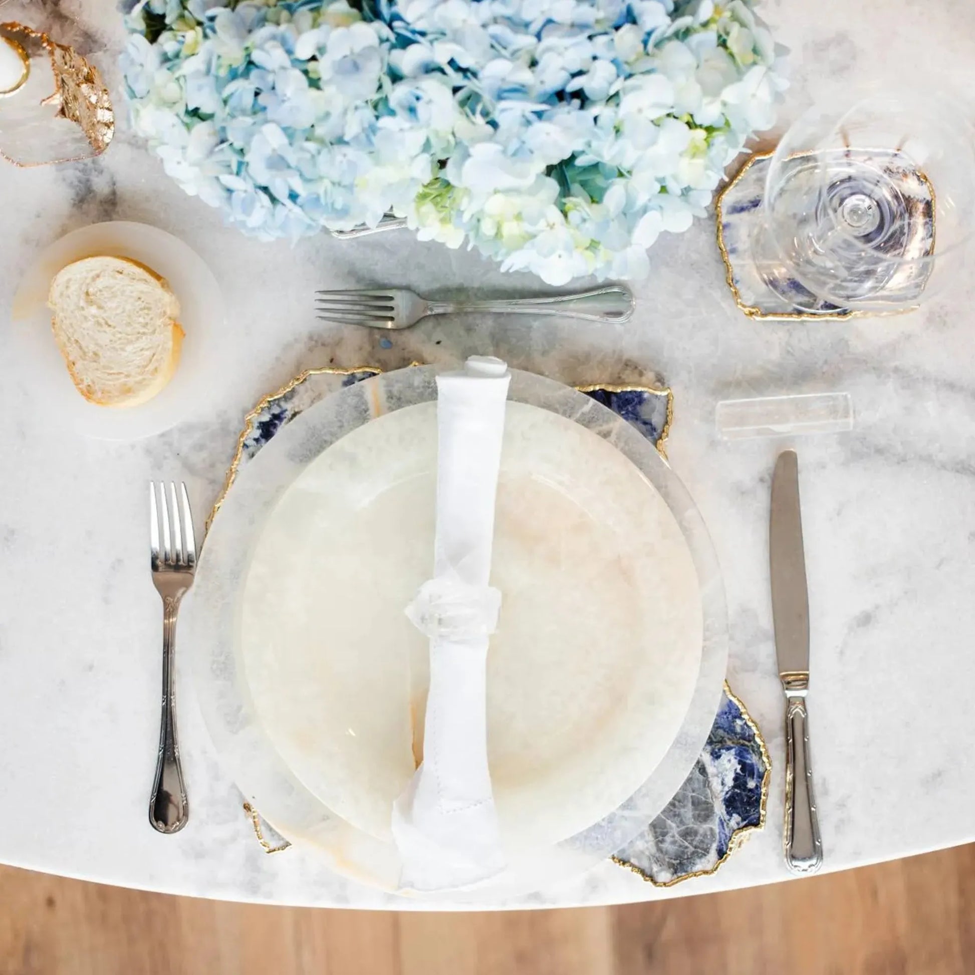 Sousplat Ônix ambientado em mesa com flores azuis.