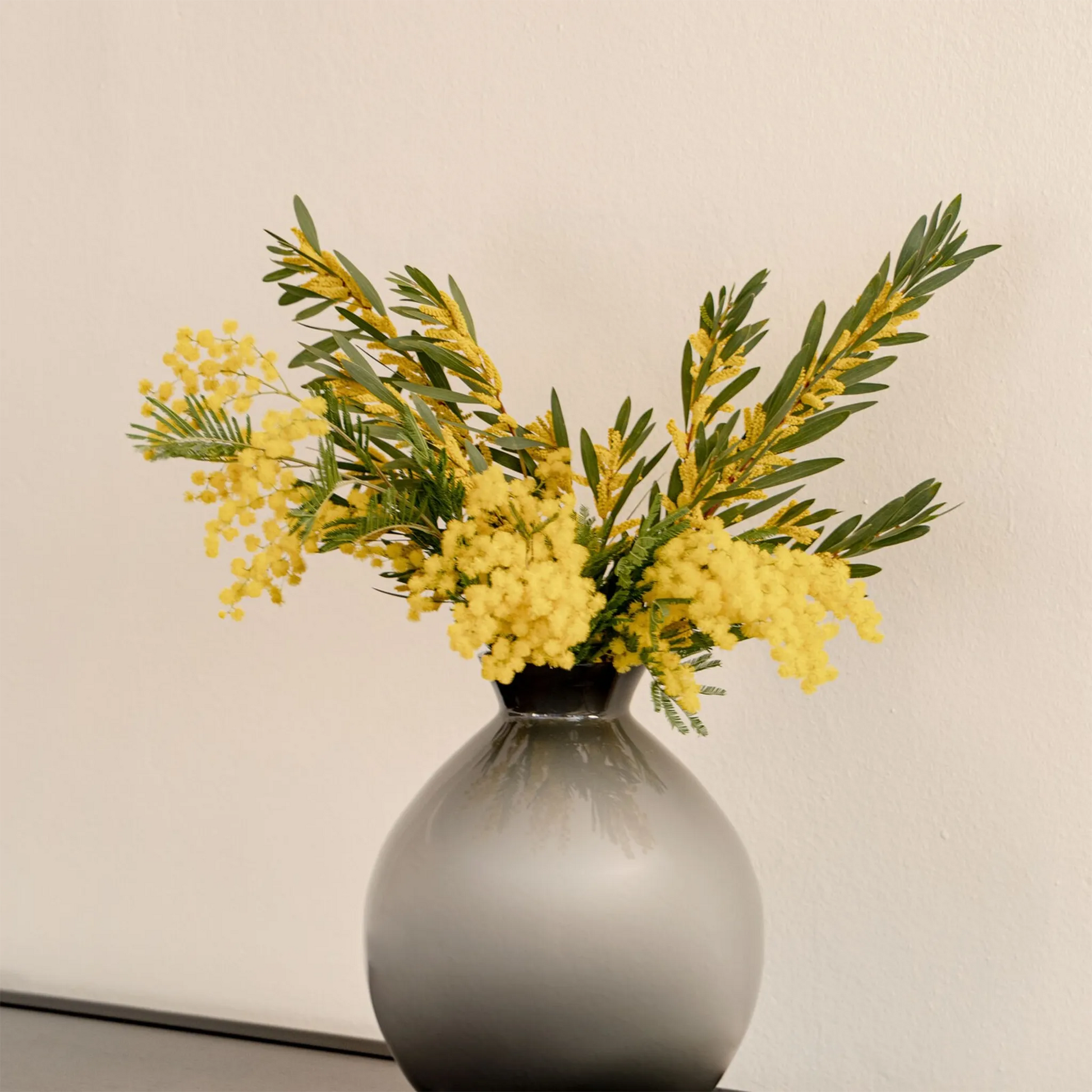 Vaso Rosenthal Silvanna Cinza ambientado com flores amarelas dentro.