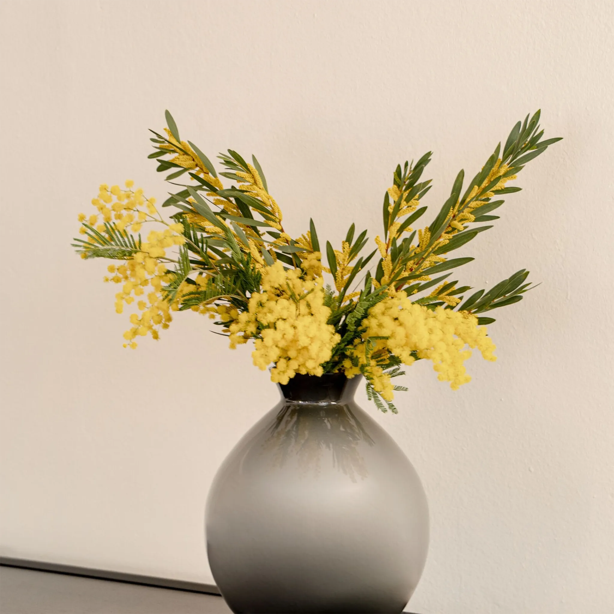 Vaso Rosenthal Silvanna Cinza ambientado com flores amarelas dentro.