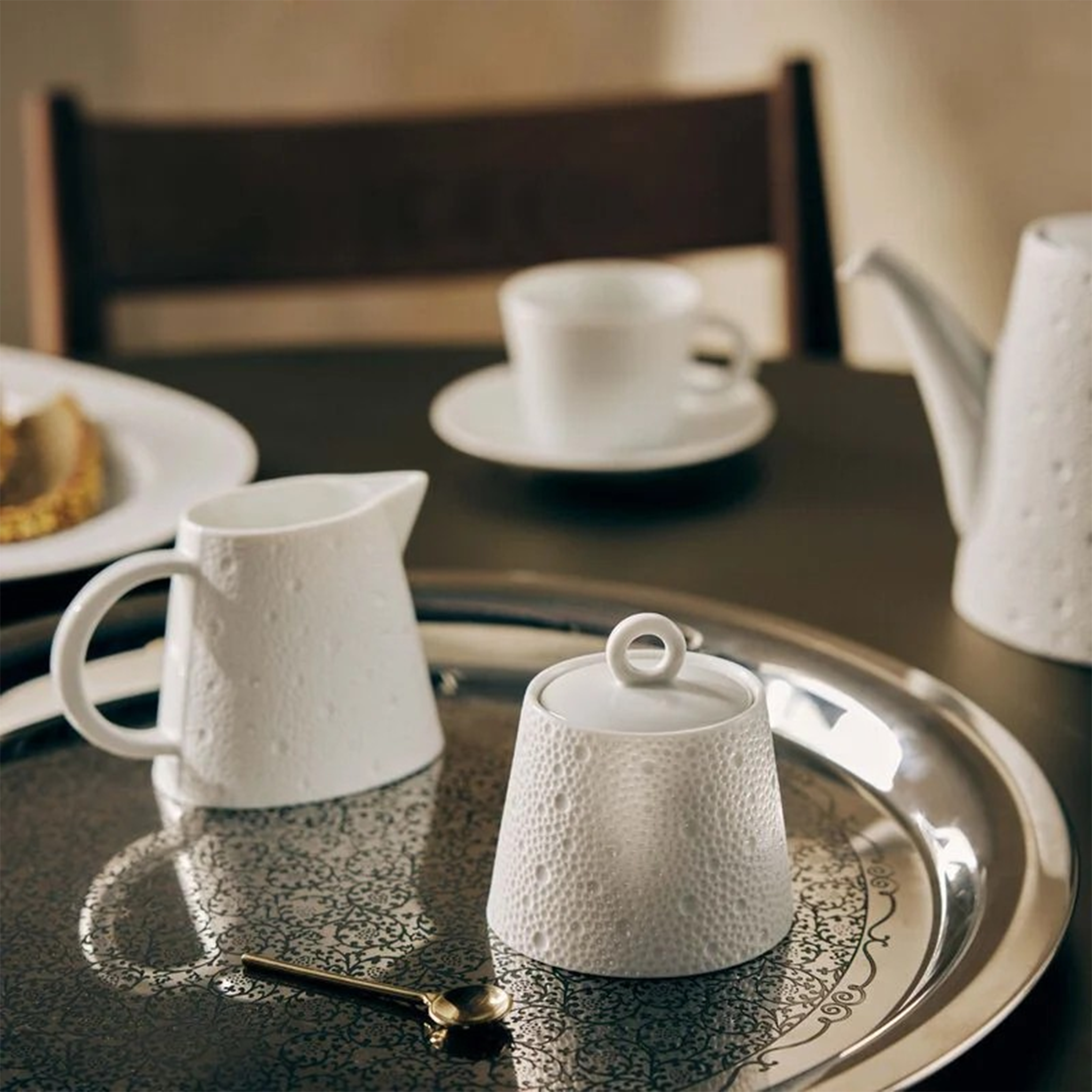 Bule Ecume Branco 1 L ambientado em mesa, em cima de uma travessa de prata, com outros utensílios da coleção Ecume Branco.