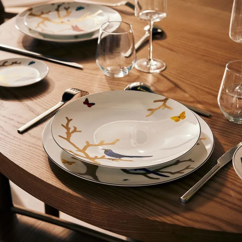 Mesa de madeira com pratos da Bernardaud Limoges, talheres e copos de vidro.