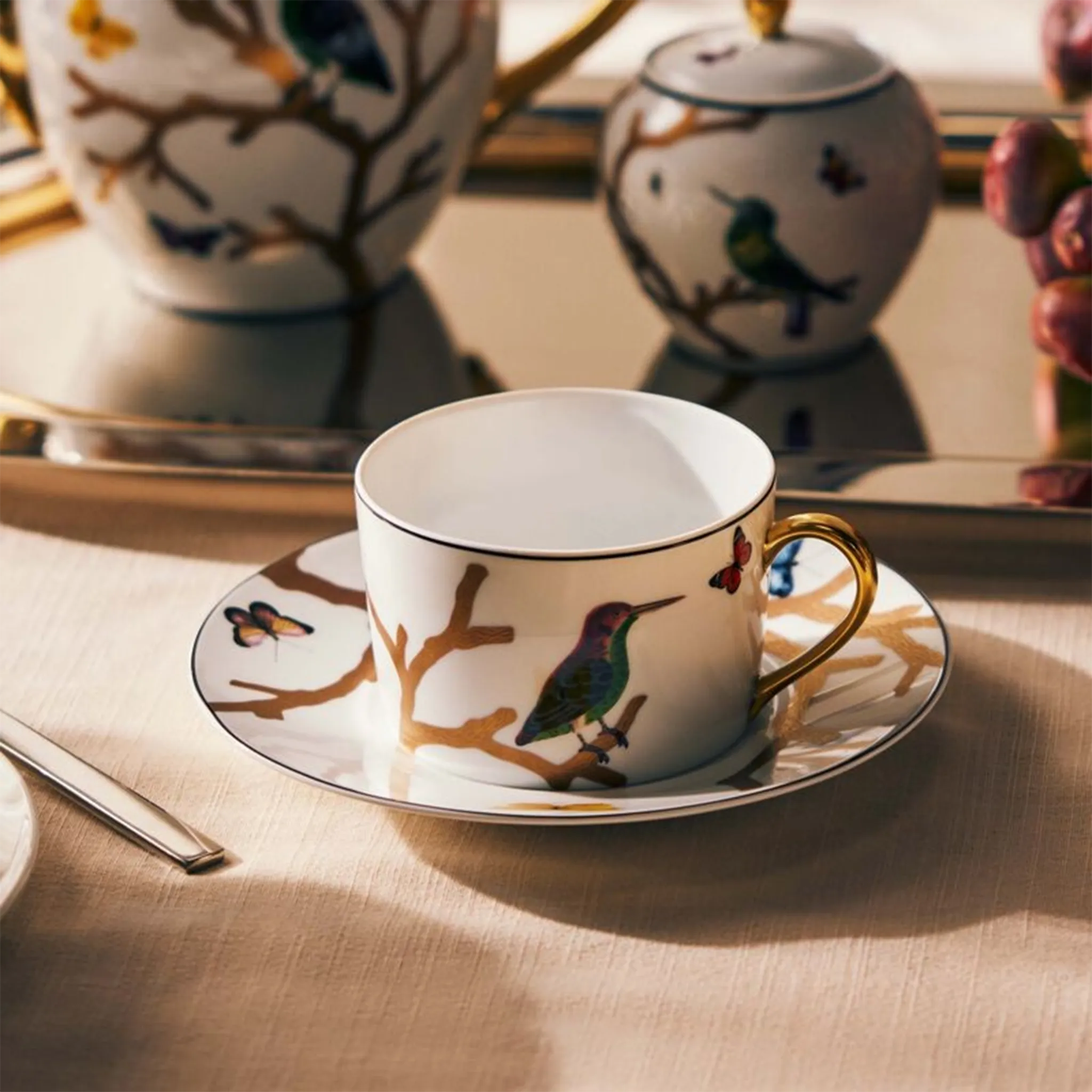 Set 2 Xícaras de Chá Aux Oiseaux ambientada em mesa com toalha de linho e outros utensílios da coleção Aux Oiseaux.