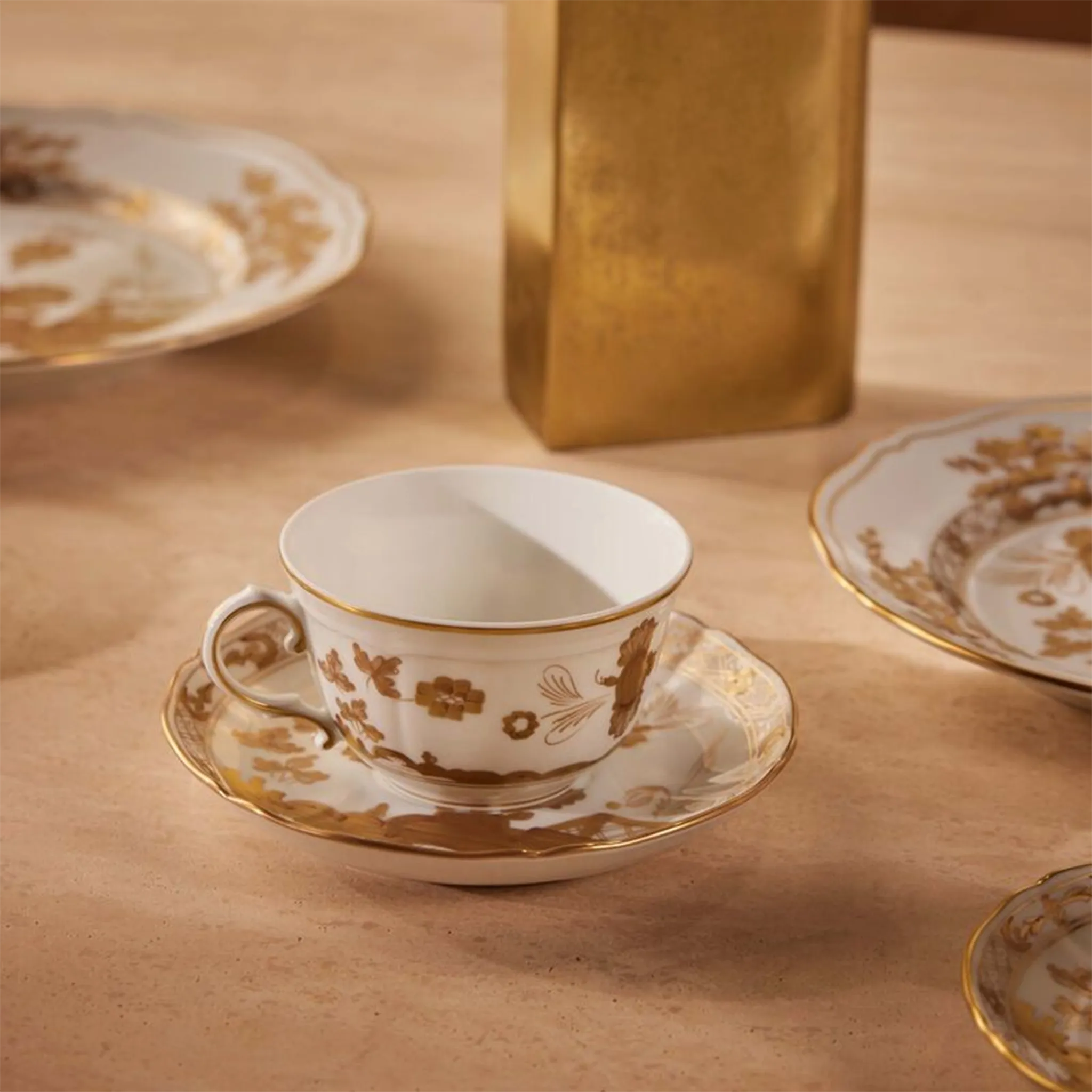 Xícara de Chá Oriente Italiano Aurum ambientada em mesa com outros itens da coleção Aurum.